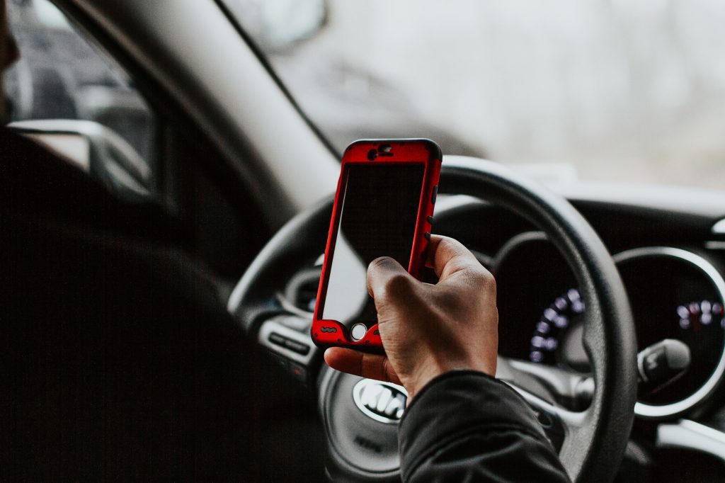Person holding red smartphone while driving