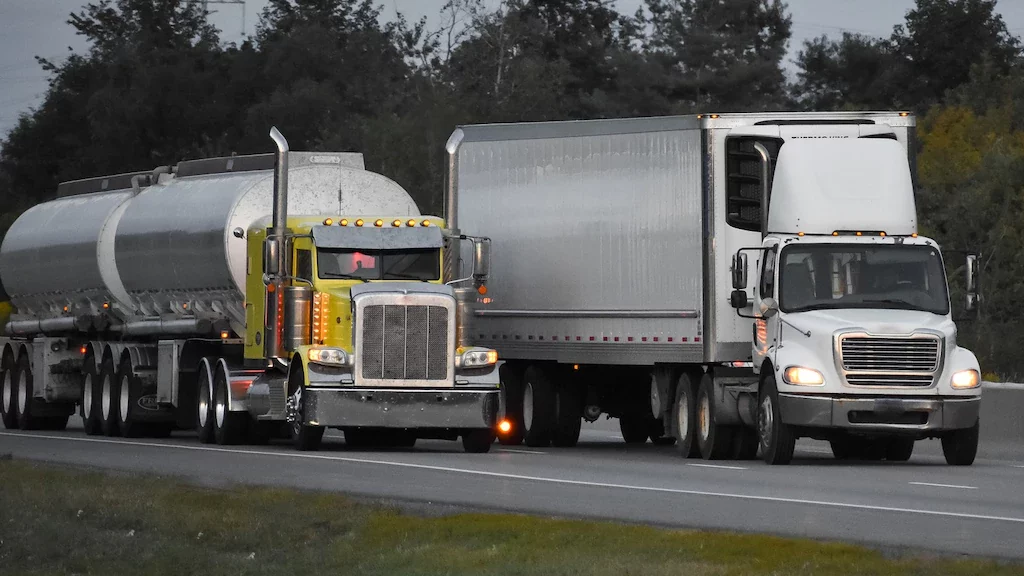 trailer-trucks-driving-road-surrounded-by-beautiful-green-trees