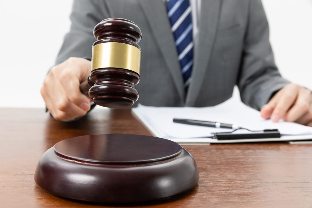 Closeup shot of a person with a gavel in hand and papers on the table