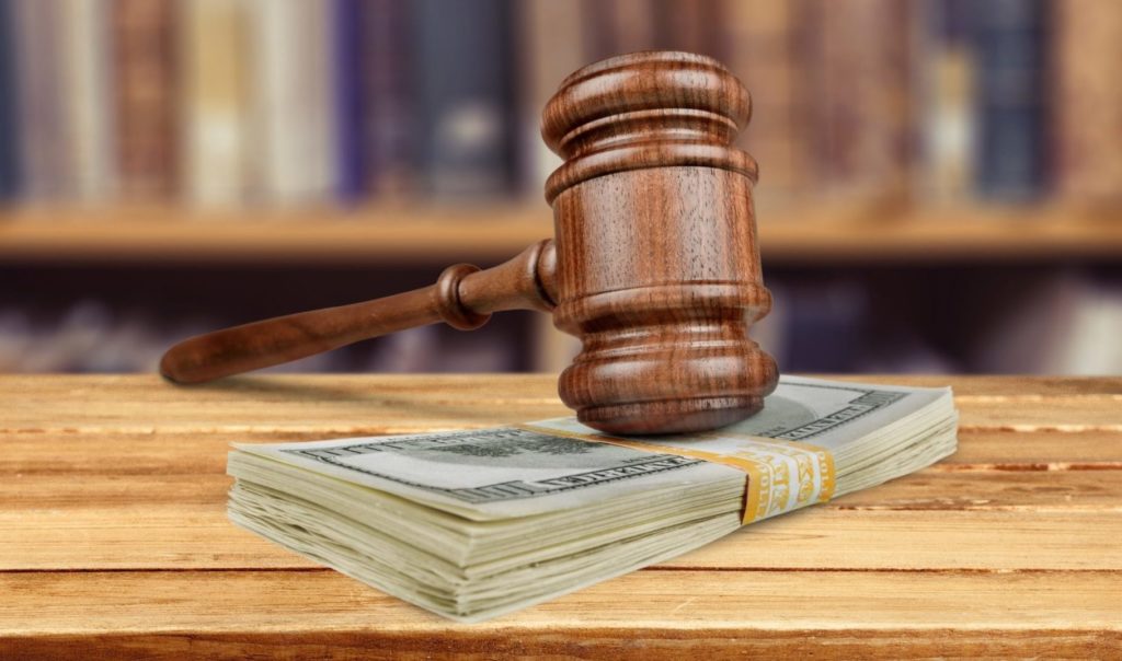 A hammer hitting money at a trial of punitive damages