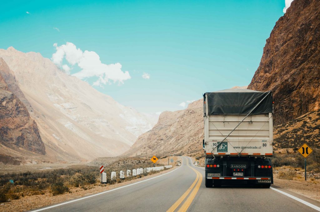 semi-truck on the road between mountains