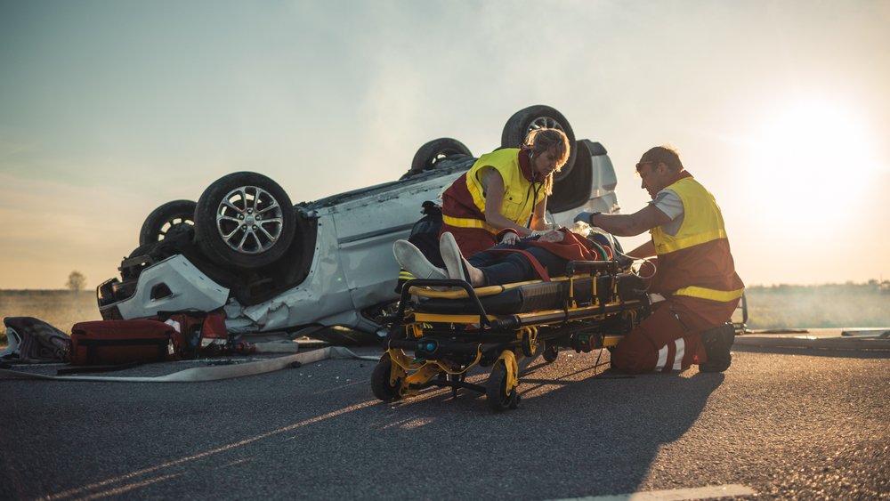 two rescuers assisting a person who has been in a car accident